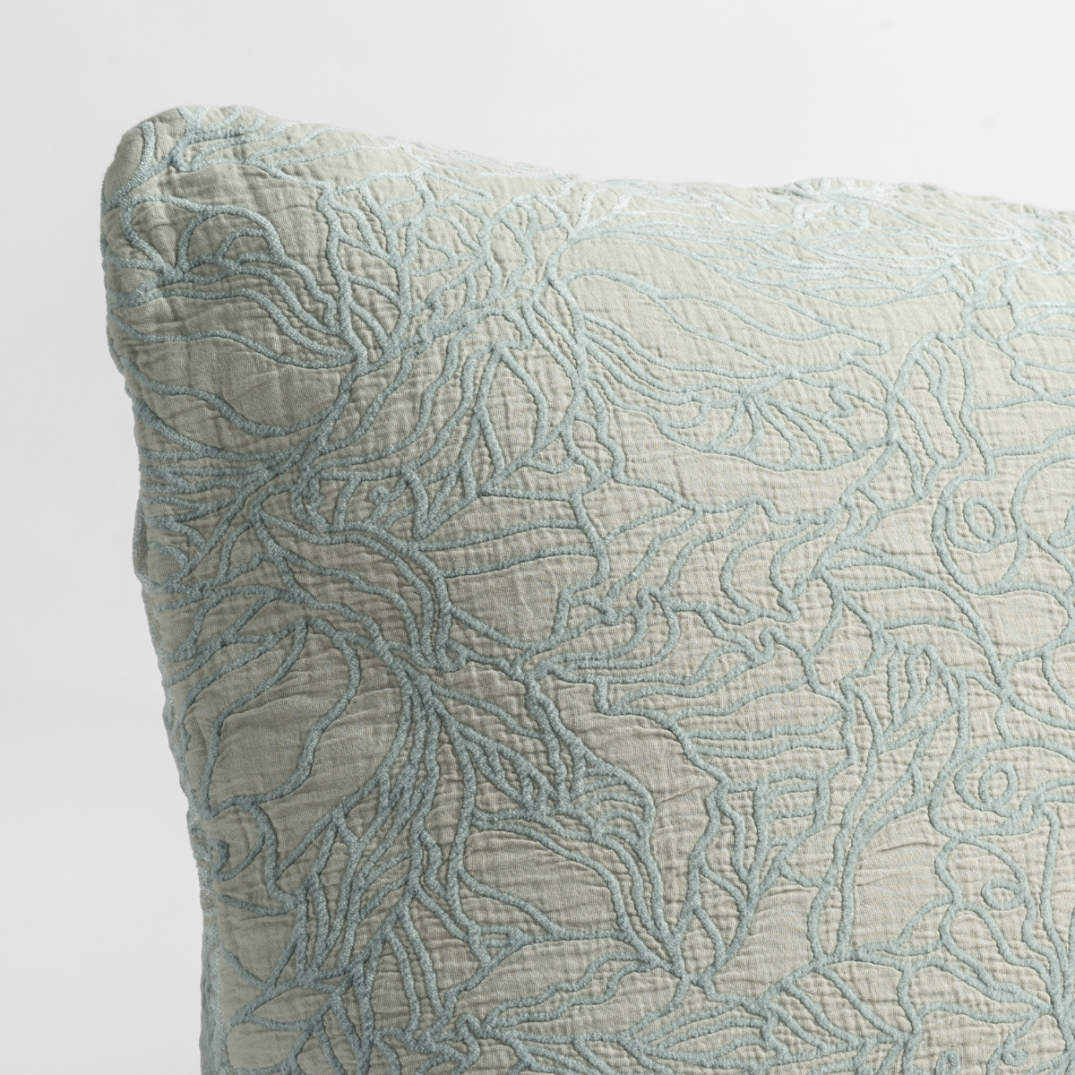 Cloud: close up of the cotton jacquard corner of a pillow cushion with a single-line floral pattern.