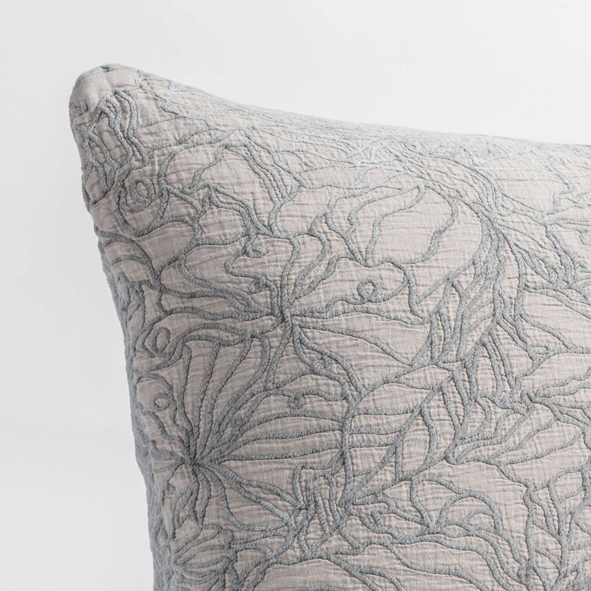 Fog: close up of the cotton jacquard corner of a pillow cushion with a single-line floral pattern.