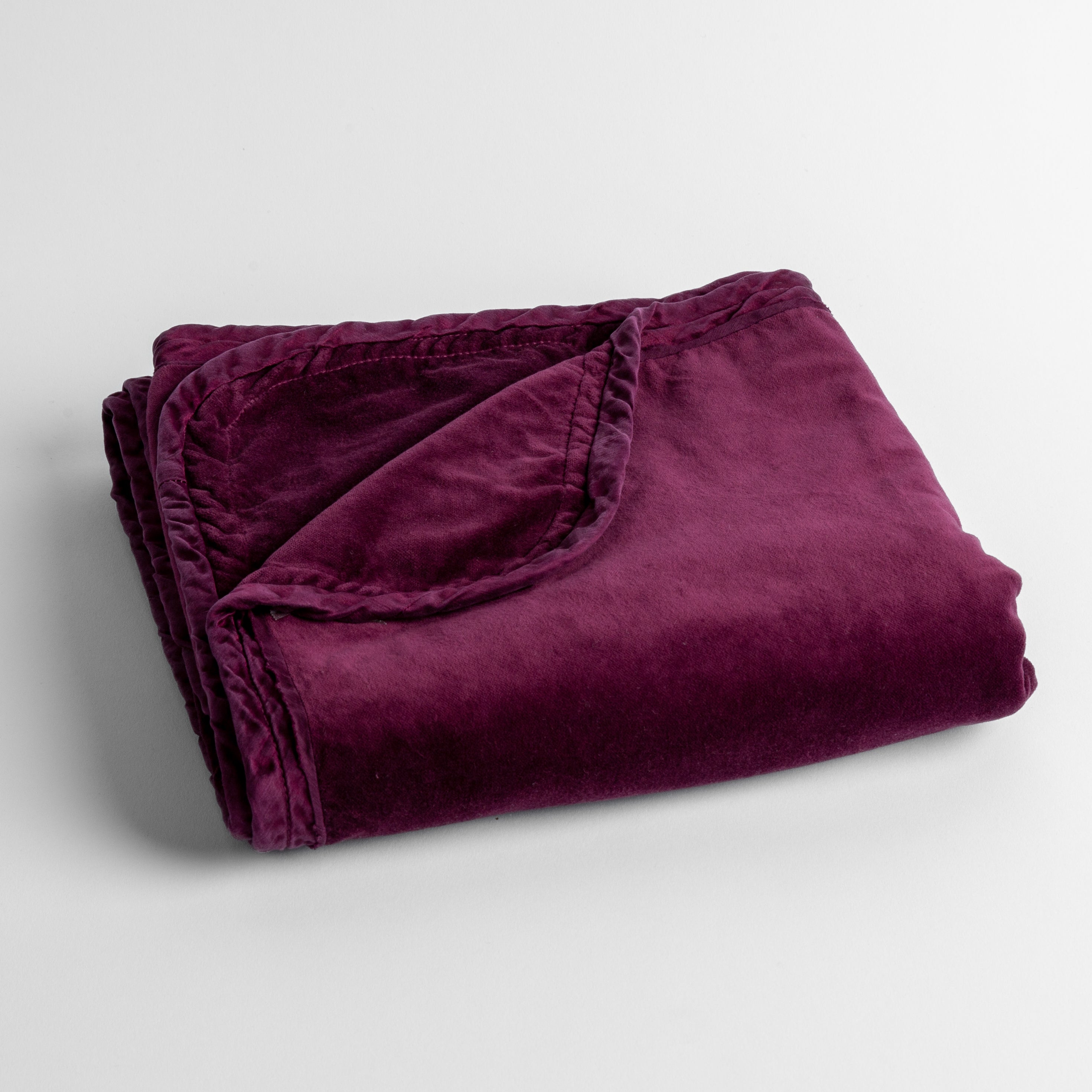 Fig: cotton velvet baby blanket trimmed with charmeuse, folded with a covern folded back to show trim contrast; shot overhead and at a slight angle against a white background.