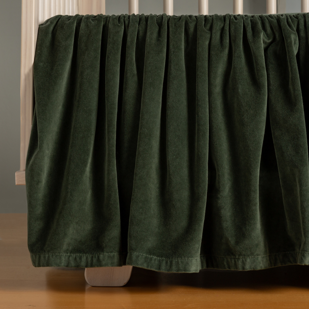 Juniper: coton velvet crib skirt shown on a light wood crib.