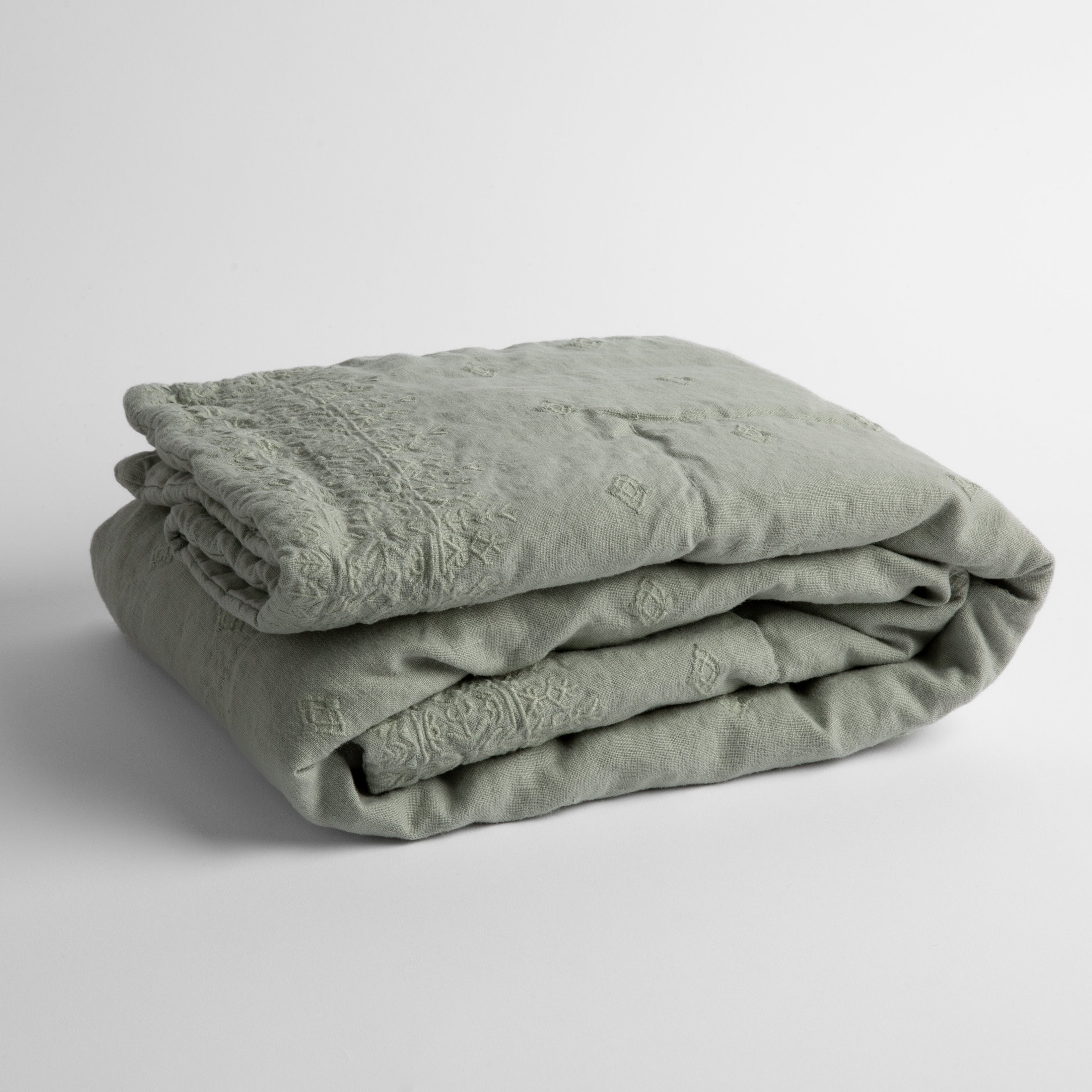 Eucalyptus: embroidered linen baby blanket folded and shown overhead from a slight angle against a white background.