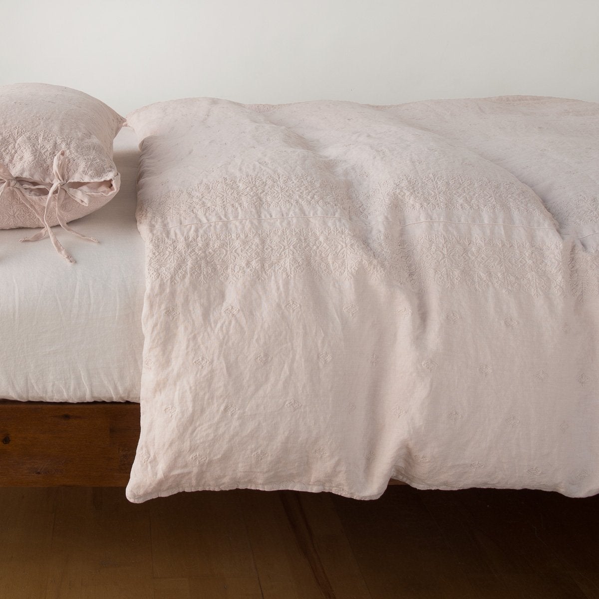 Pearl: lightly rumpled duvet cover on a monochromatic bed against a white background - side view.