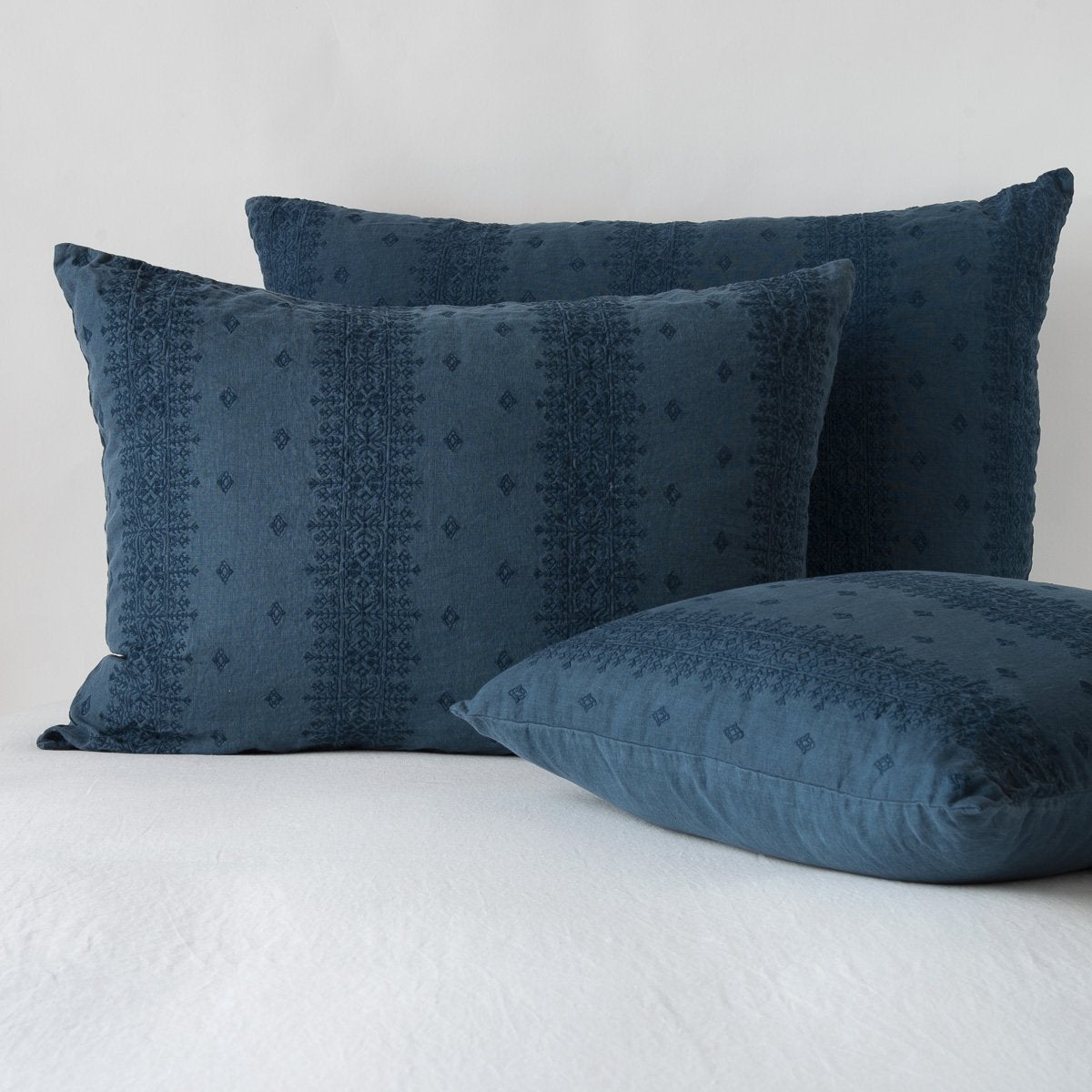 Midnight: two shams leaning upright and one laying flat at an angle, against a white background.