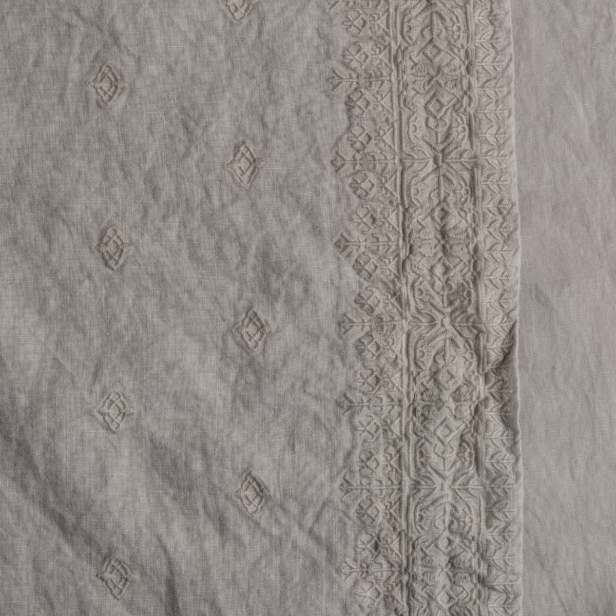 Fog: A close up of embroidered midweight linen fabric in fog, a neutral-warm, soft mid-tone grey.