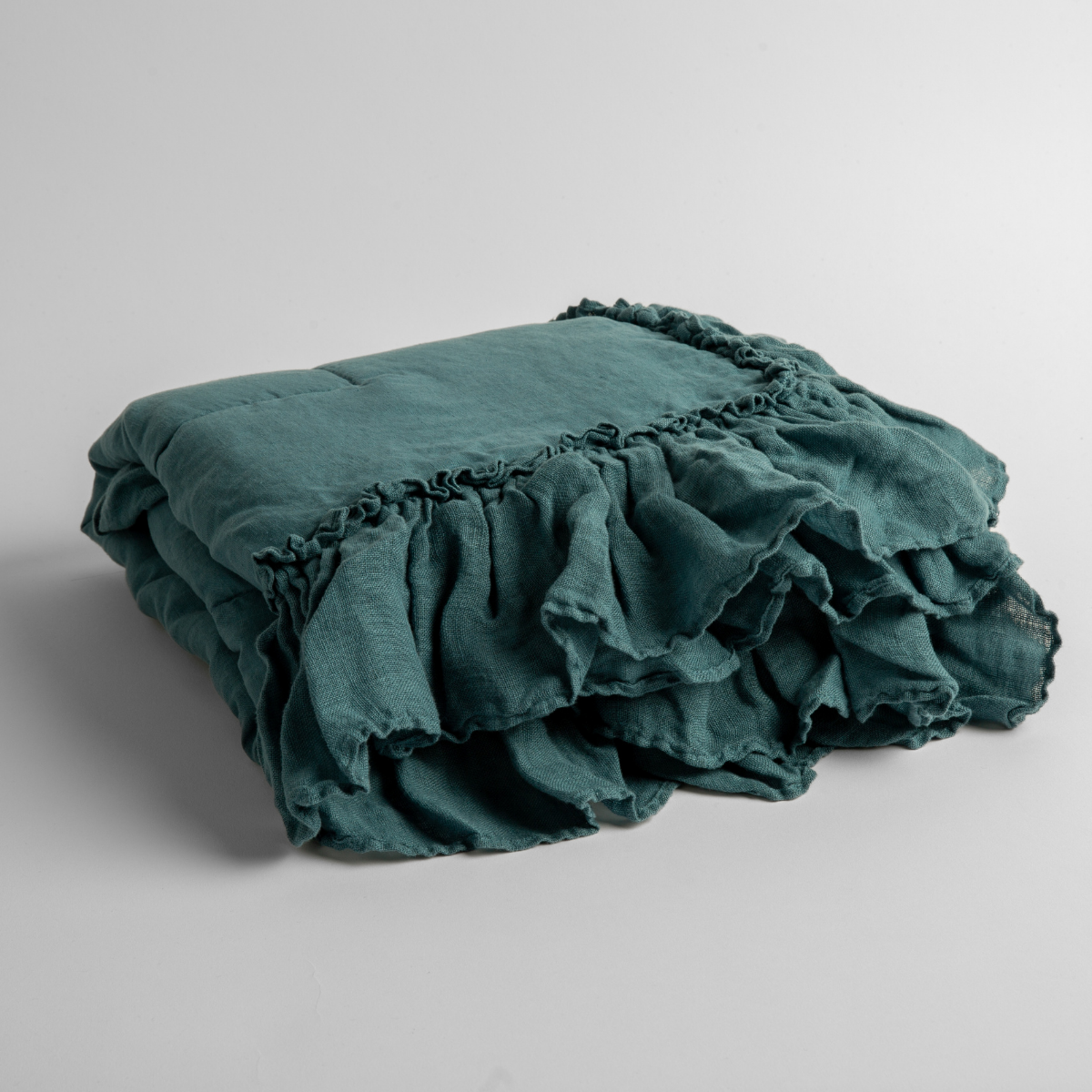 Cenote: a folded linen with linen whisper ruffled blanket folded and positioned to show the ruffle detail against a white background and slightly overhead.