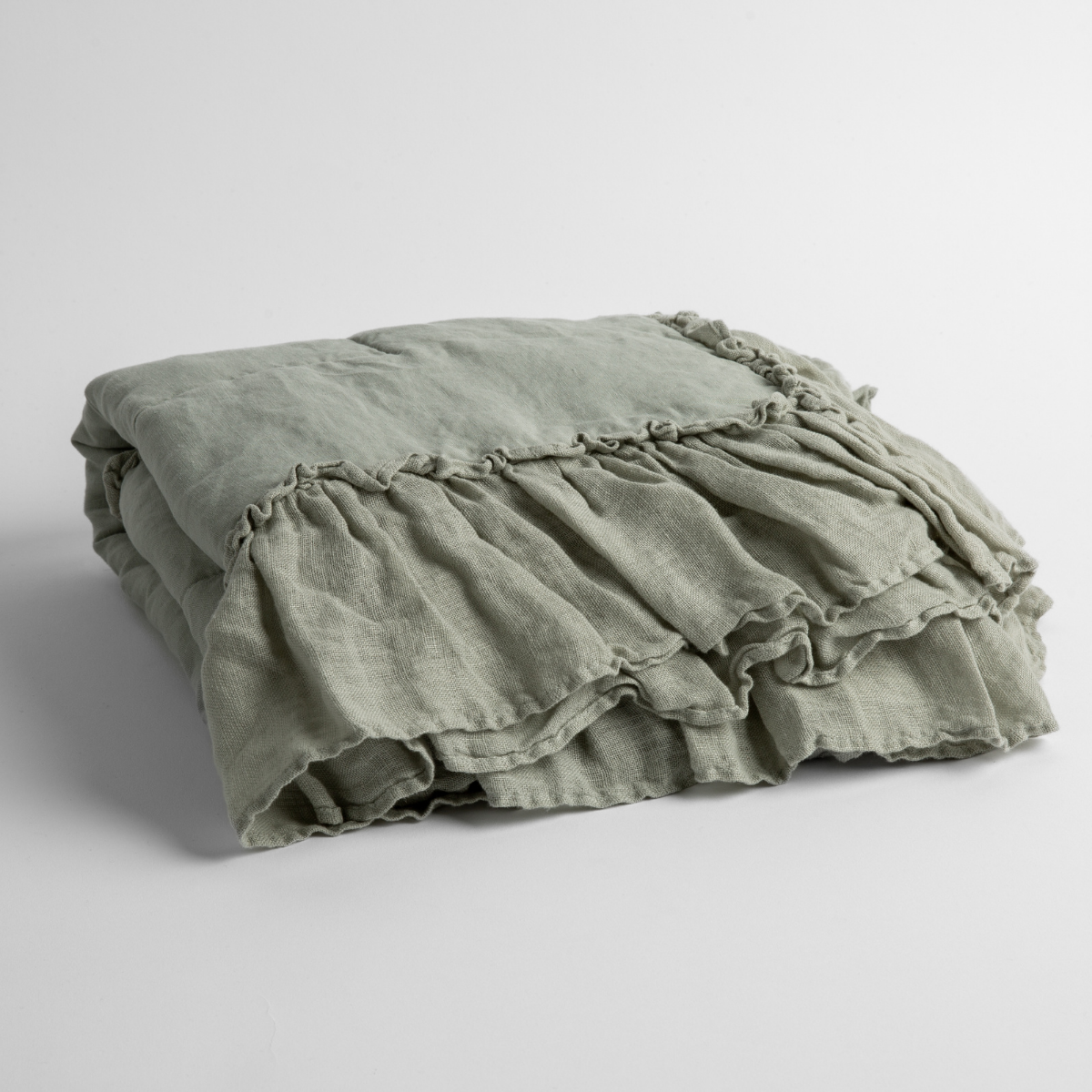 Eucalyptus: a folded linen with linen whisper ruffled blanket folded and positioned to show the ruffle detail against a white background and slightly overhead.