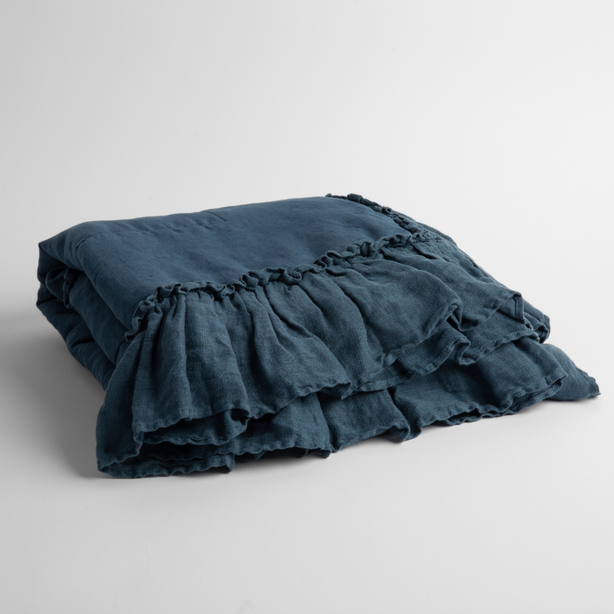 Midnight: a folded linen with linen whisper ruffled blanket folded and positioned to show the ruffle detail against a white background and slightly overhead.