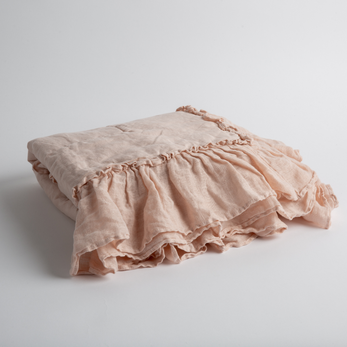 Pearl: a folded linen with linen whisper ruffled blanket folded and positioned to show the ruffle detail against a white background and slightly overhead.