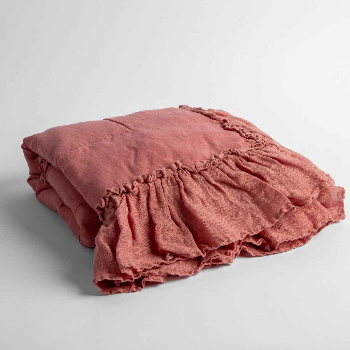 Poppy: a folded linen with linen whisper ruffled blanket folded and positioned to show the ruffle detail against a white background and slightly overhead.