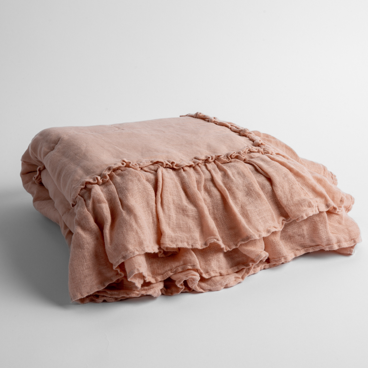 Rouge: a folded linen with linen whisper ruffled blanket folded and positioned to show the ruffle detail against a white background and slightly overhead.