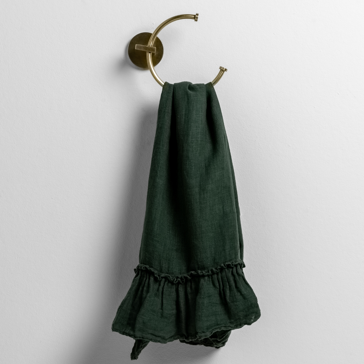 linen whisper guest towel folded and draped through a towel hook against a white background.