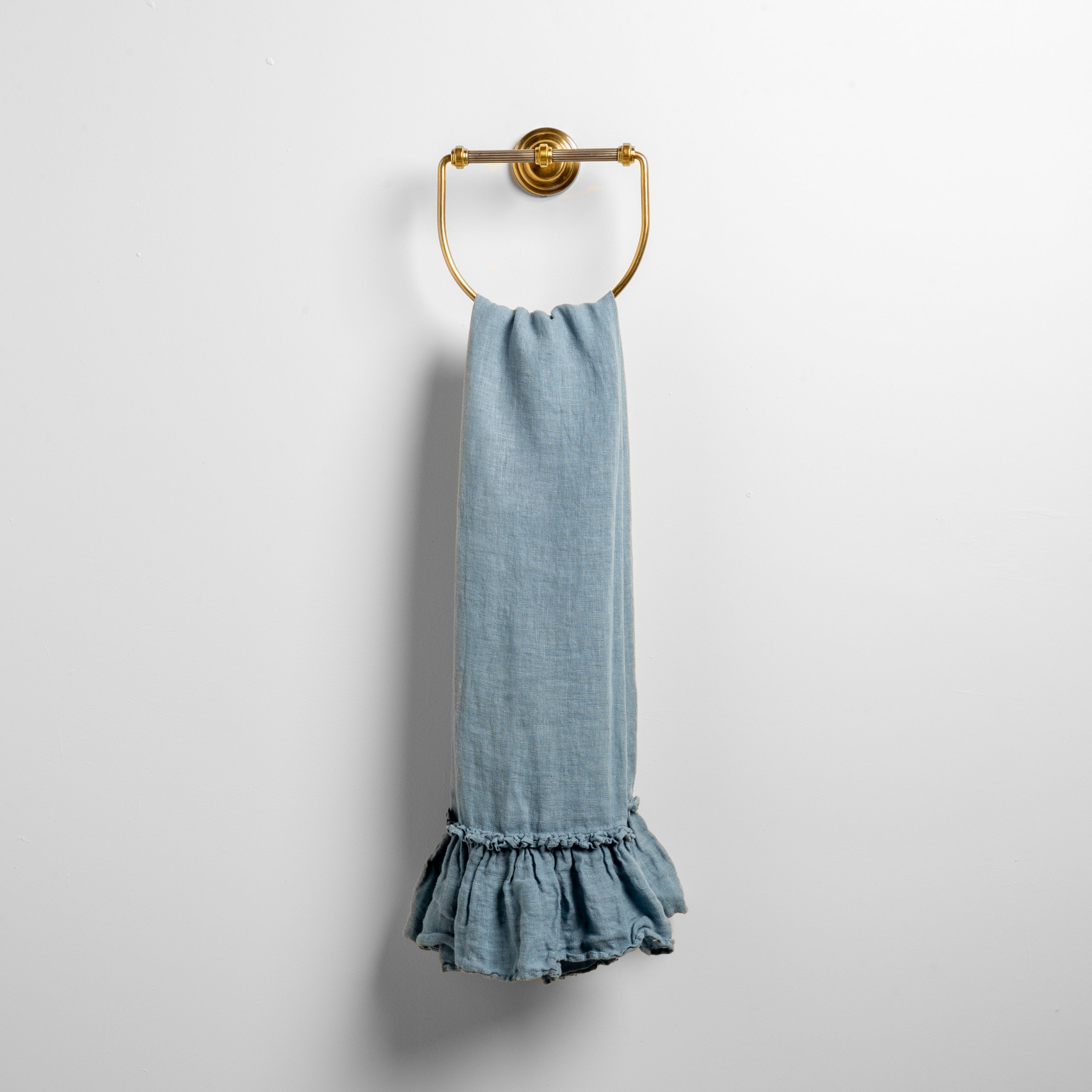 Tahoe Blue: guest towel draped through a decorative brass towel ring, against a white wall.