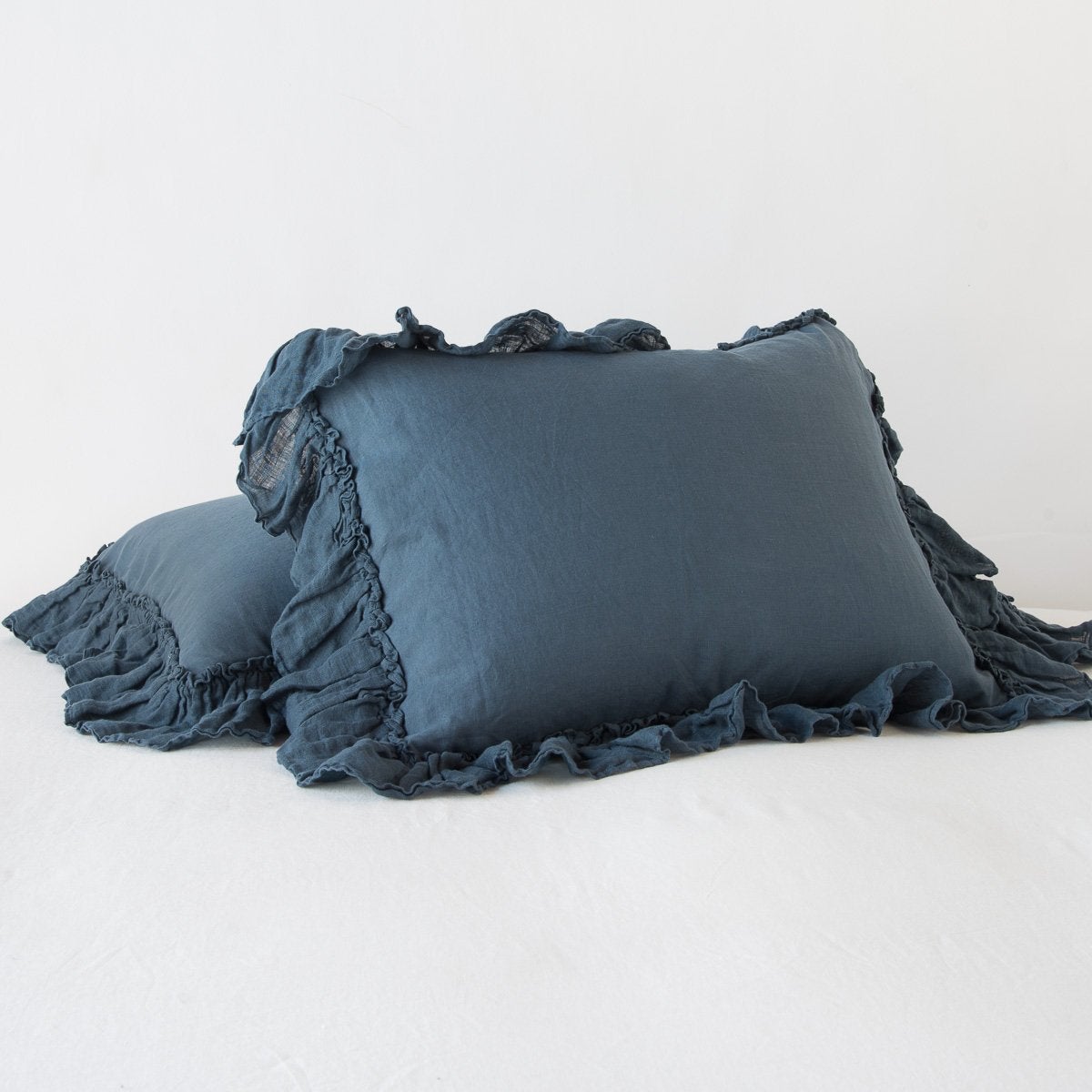 Midnight: standard sham leaning against a king sham laying flat, on a plain background.