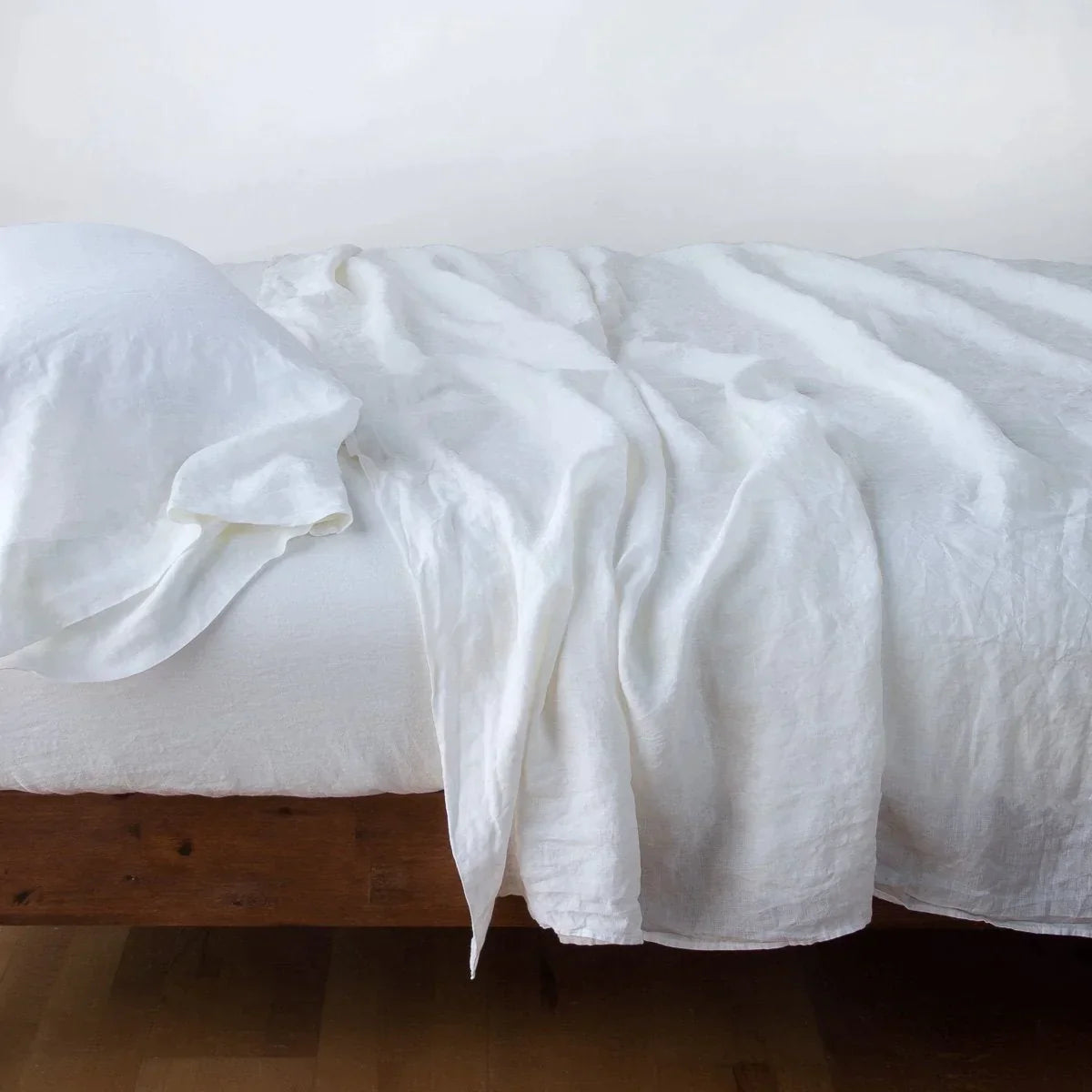 White: Rumpled linen sheeting with matching sleeping pillow - side view.