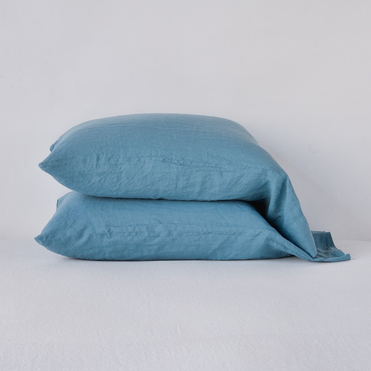Cenote: Two sleeping pillows neatly stacked against a white background - side view.