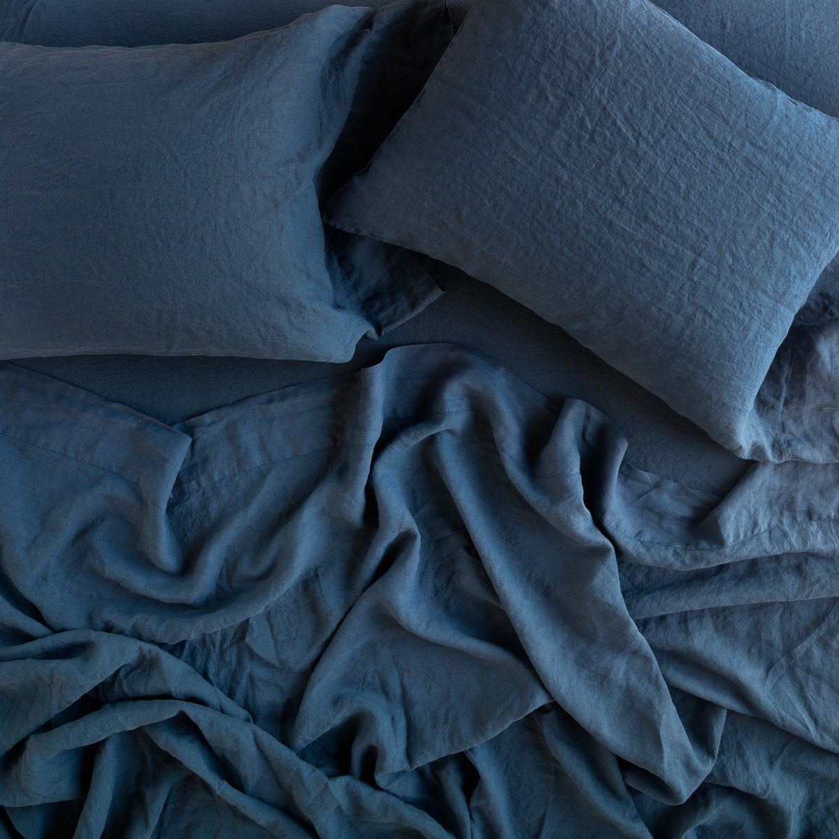 Midnight: sleeping pillows laid flat on rumpled matching sheeting - overhead view.