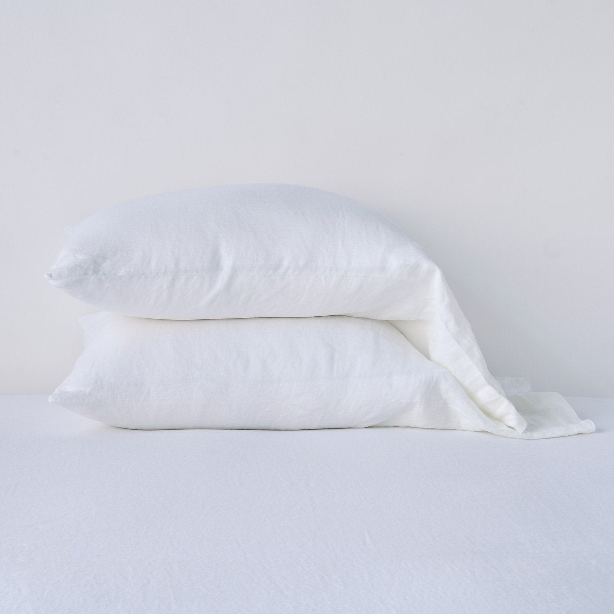 White: Two sleeping pillows neatly stacked against a white background - side view.
