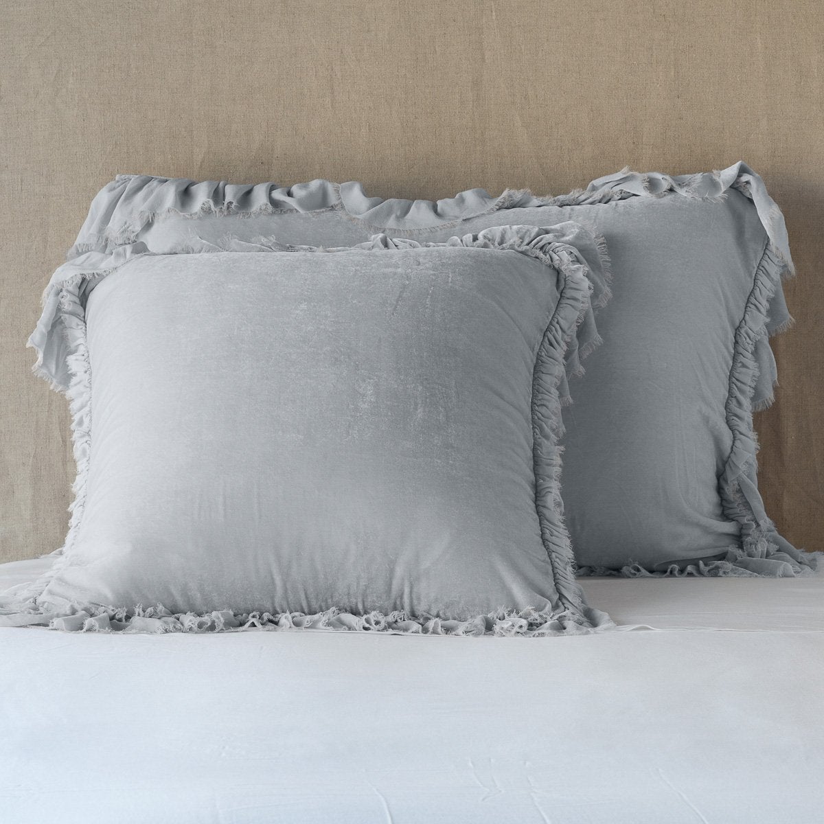 Sterling: shams leaning upright on white sheets against a neutral headboard.