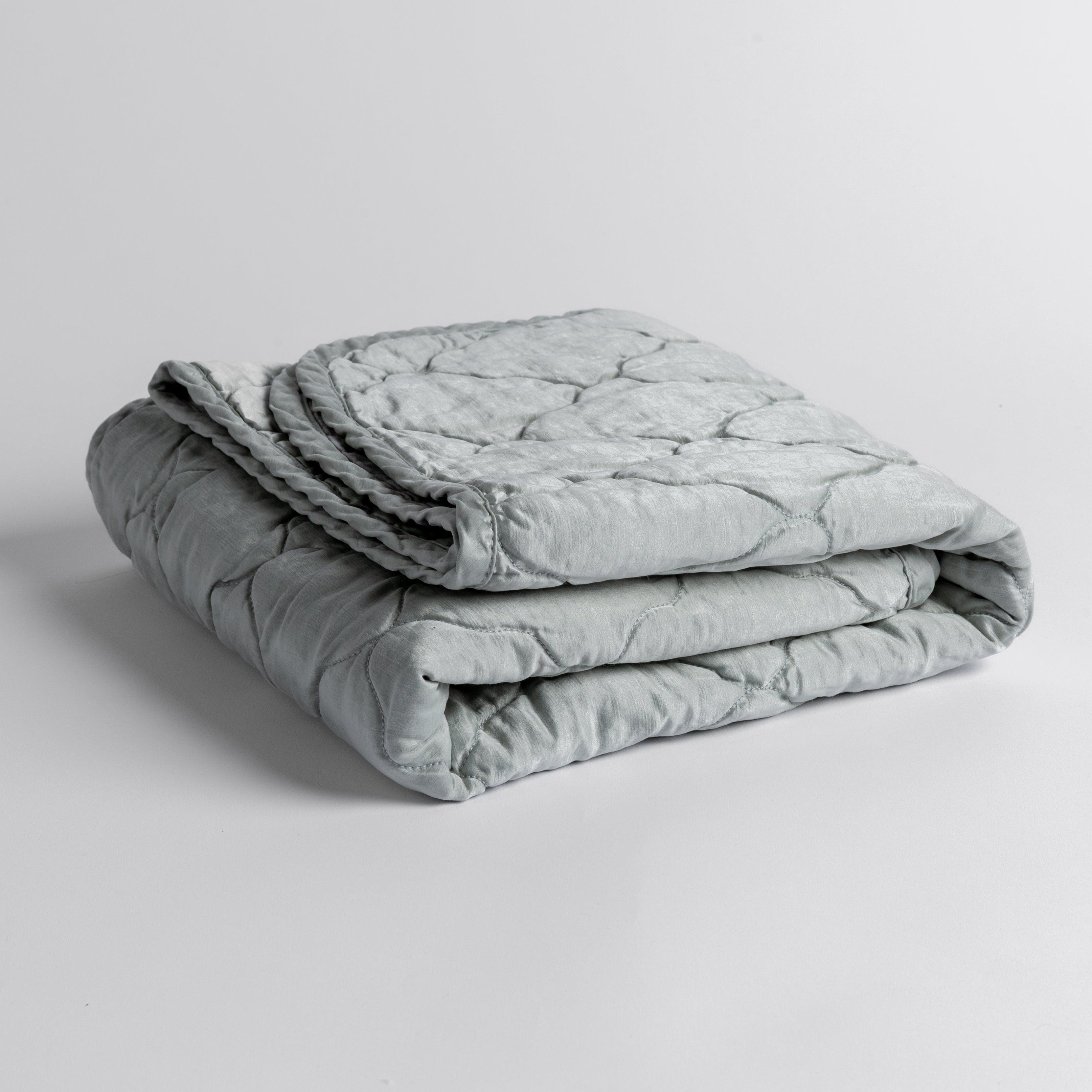 Cloud: quilted charmeuse blanket folded and shown against a white background from a slight overhead angle.
