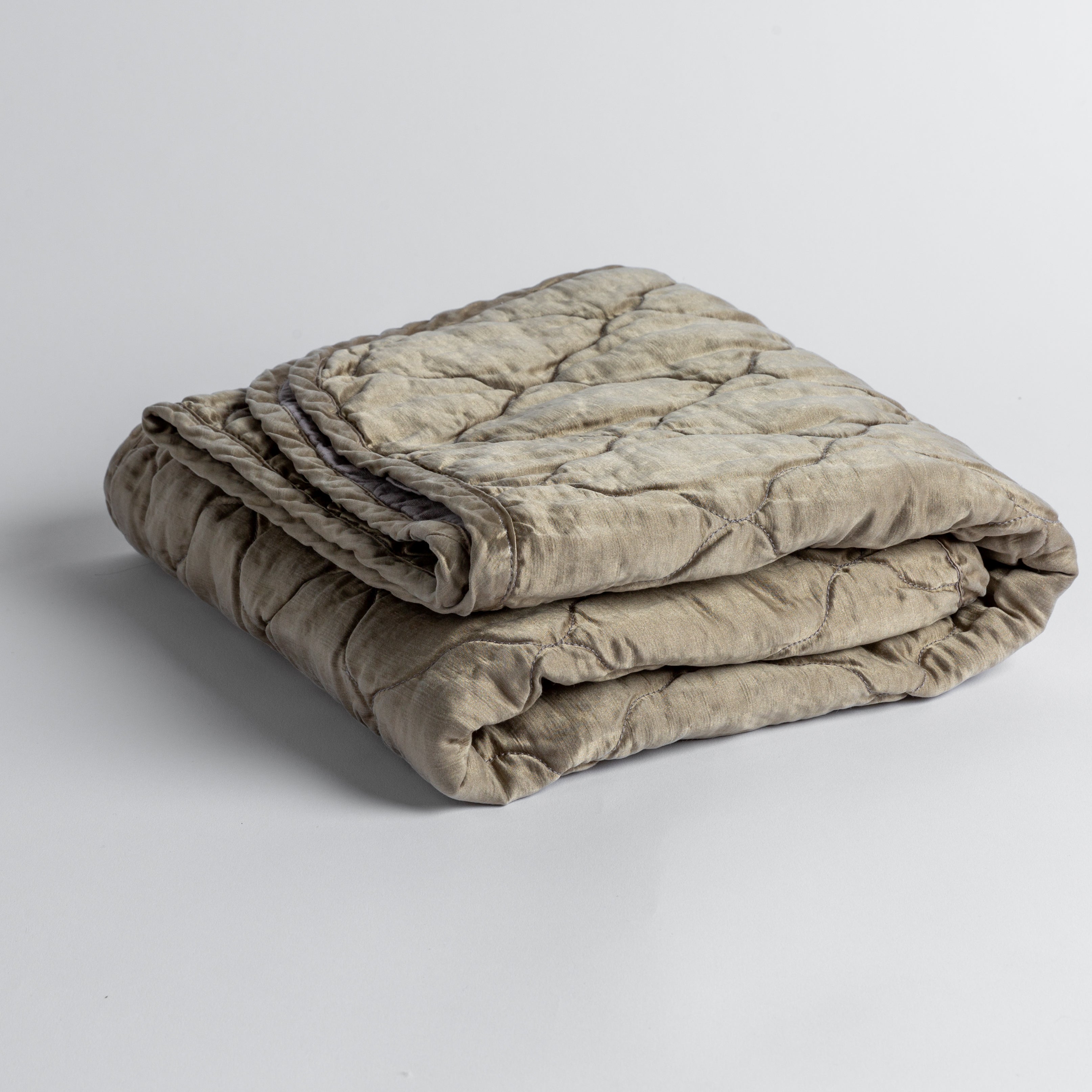 Moonlight: quilted charmeuse blanket folded and shown against a white background from a slight overhead angle.