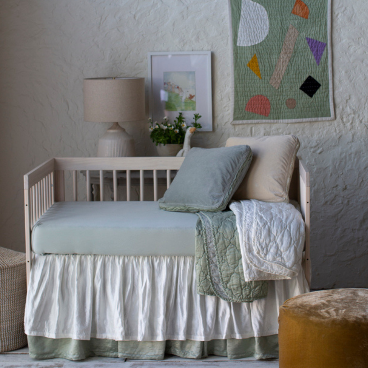 : Crib sheet in eucalyptus shown in a soft green and cream toned nursery with varied textures.