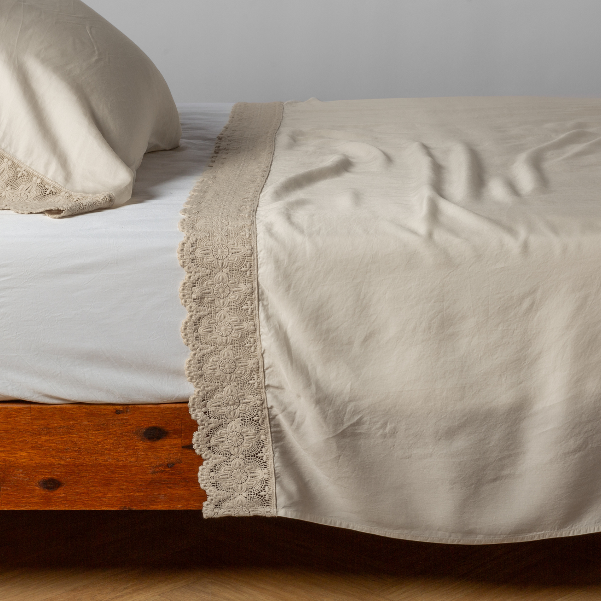 matching cotton lace trimmed flat sheet and pillowcase shown with simple white sheet - side view.