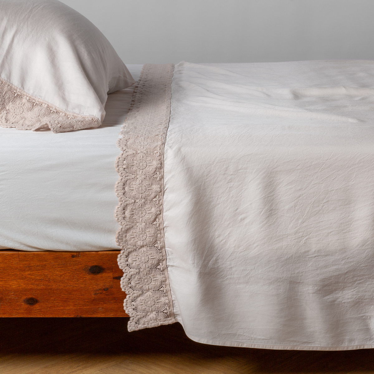 matching cotton lace trimmed flat sheet and pillowcase shown with simple white sheet - side view.