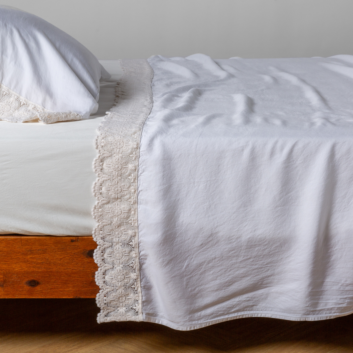 matching cotton lace trimmed flat sheet and pillowcase shown with simple white sheet - side view.