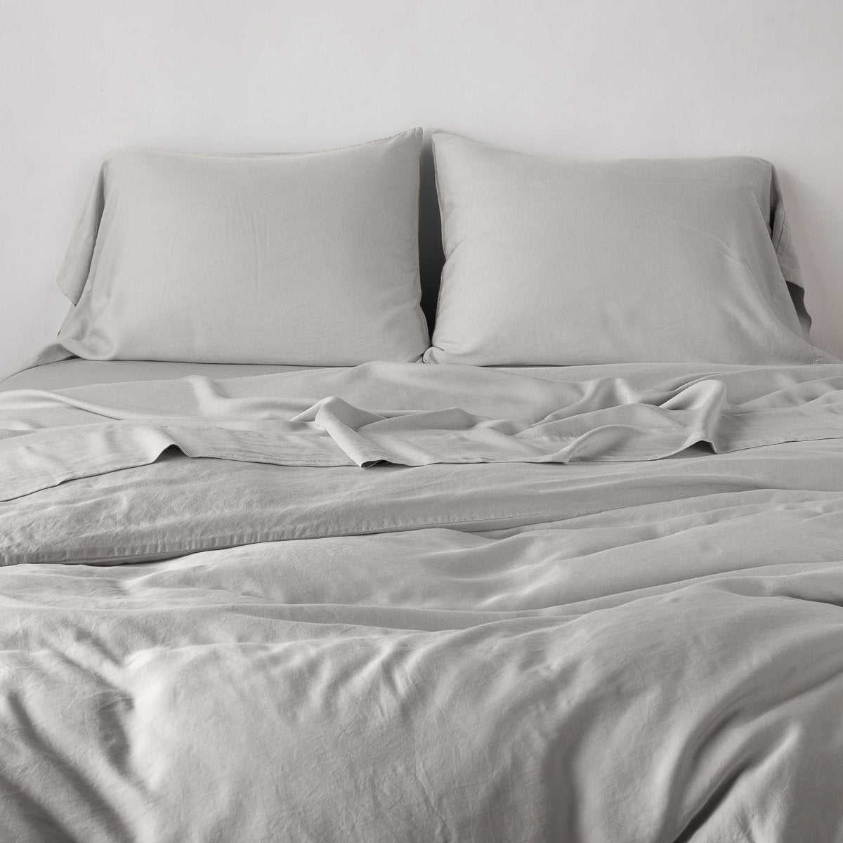 Fog: duvet cover with matching sleeping pillows and sheeting against a white wall - end of bed view.