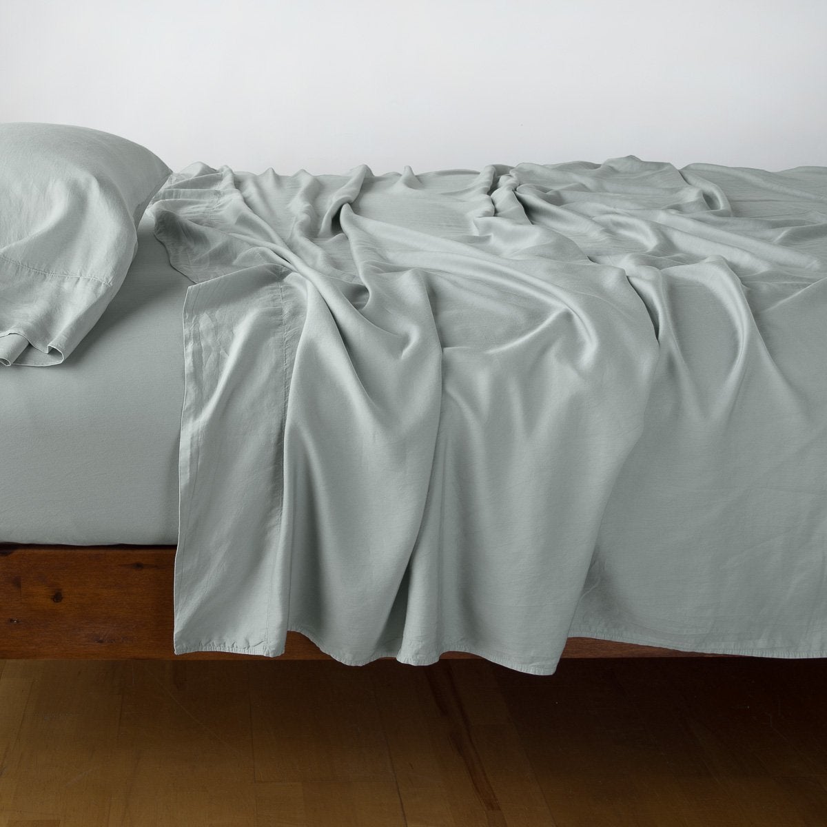 Eucalyptus: fitted sheet with matching rumpled flat sheet and sleeping pillow - side view.