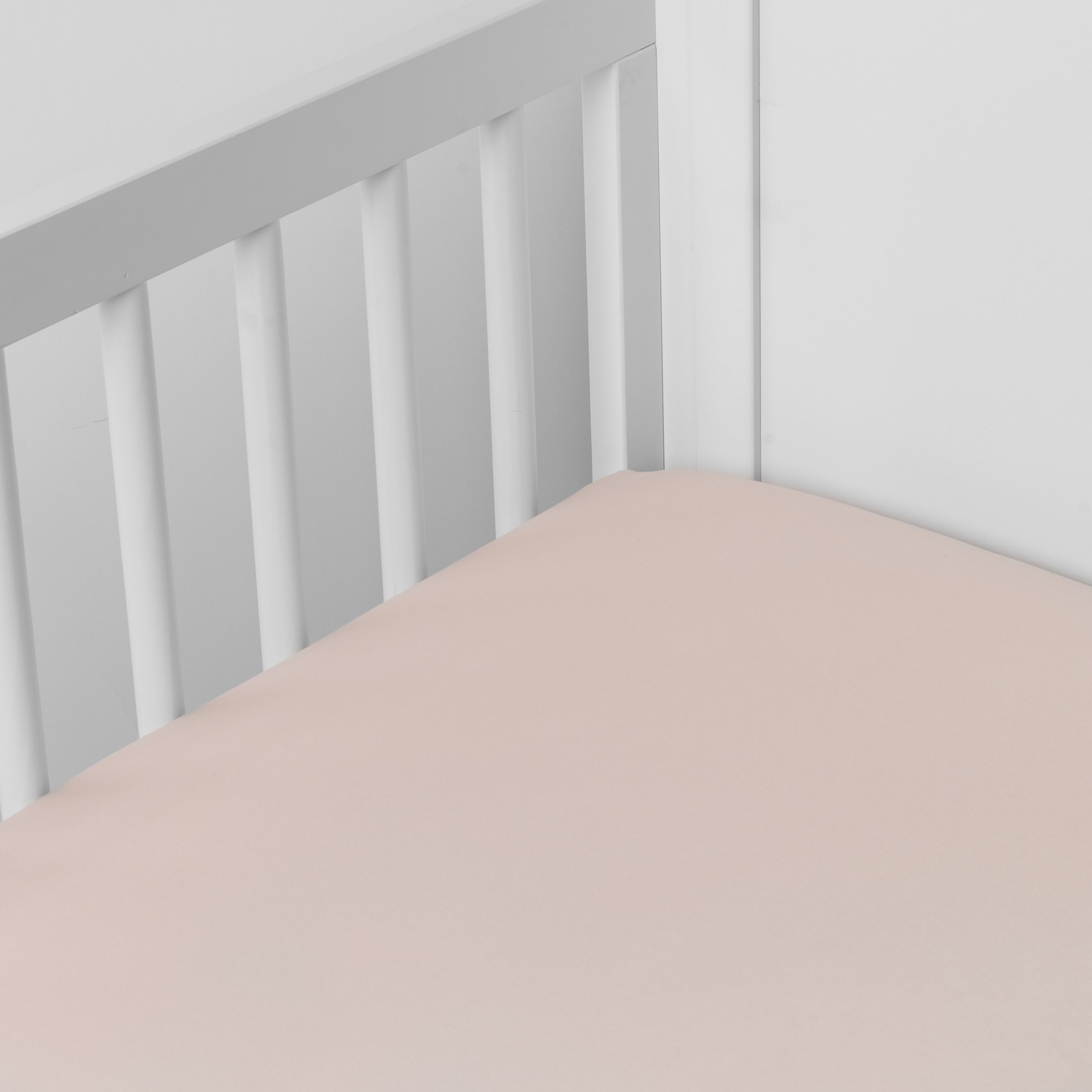Pearl: crib sheet shown on a mattress shown from overhead into the corner of a crib.