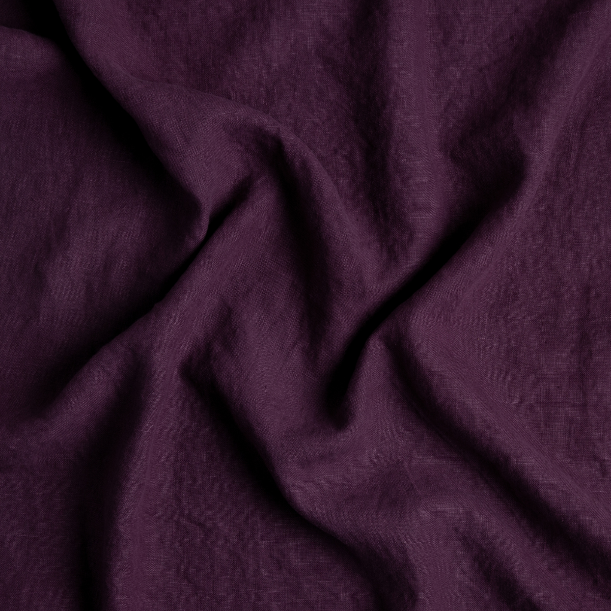 Fig: A close up of midweight linen fabric in fig, a richly saturated purple-garnet.