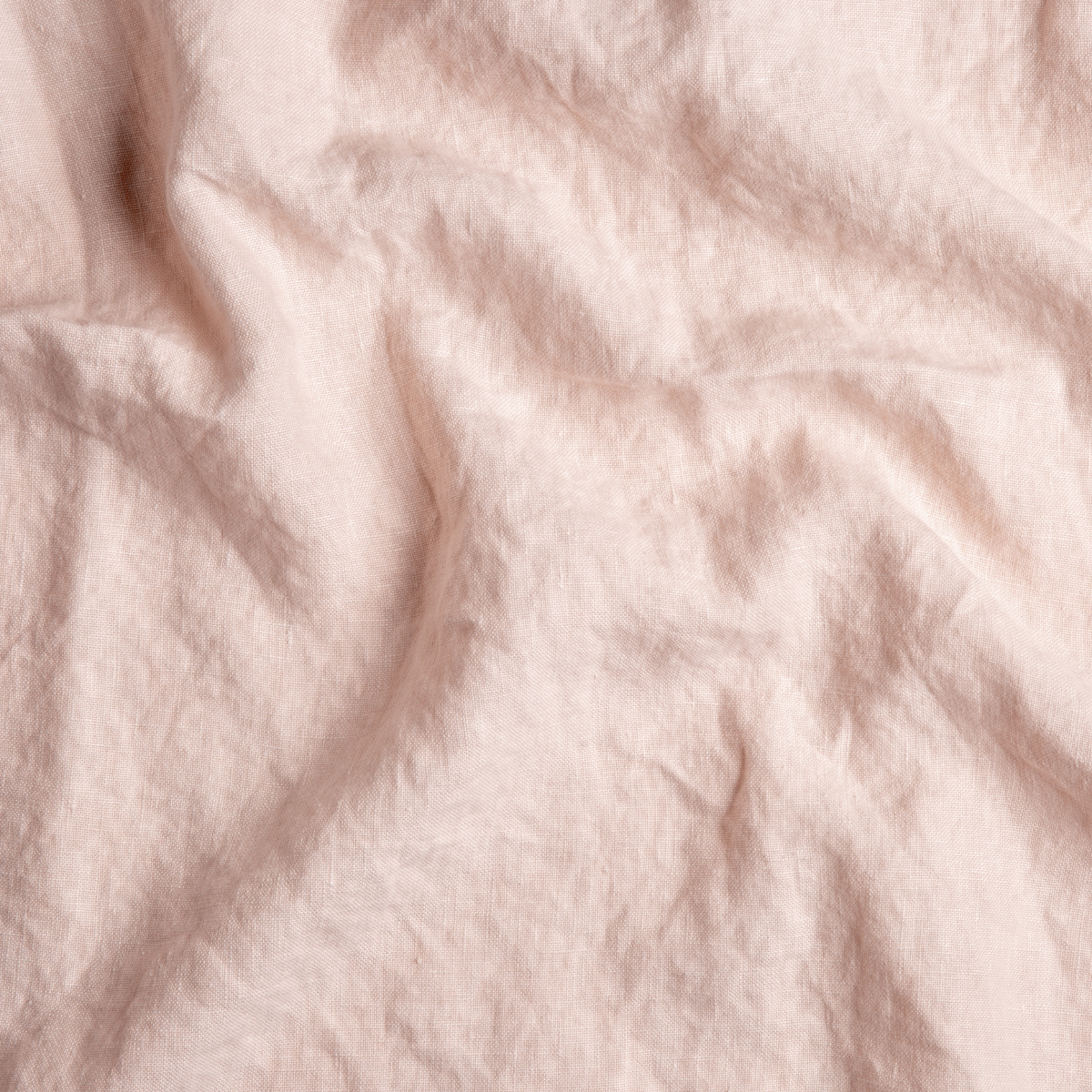 Pearl: A close up of midweight linen fabric in pearl, a nude-like, soft rose pink tone.