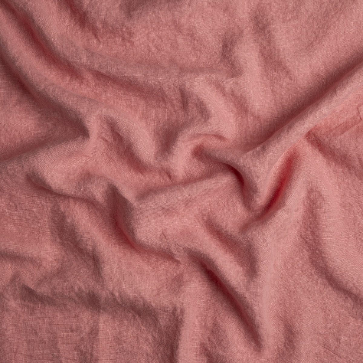 Poppy: A close up of midweight linen fabric in poppy, a warm coral pink.