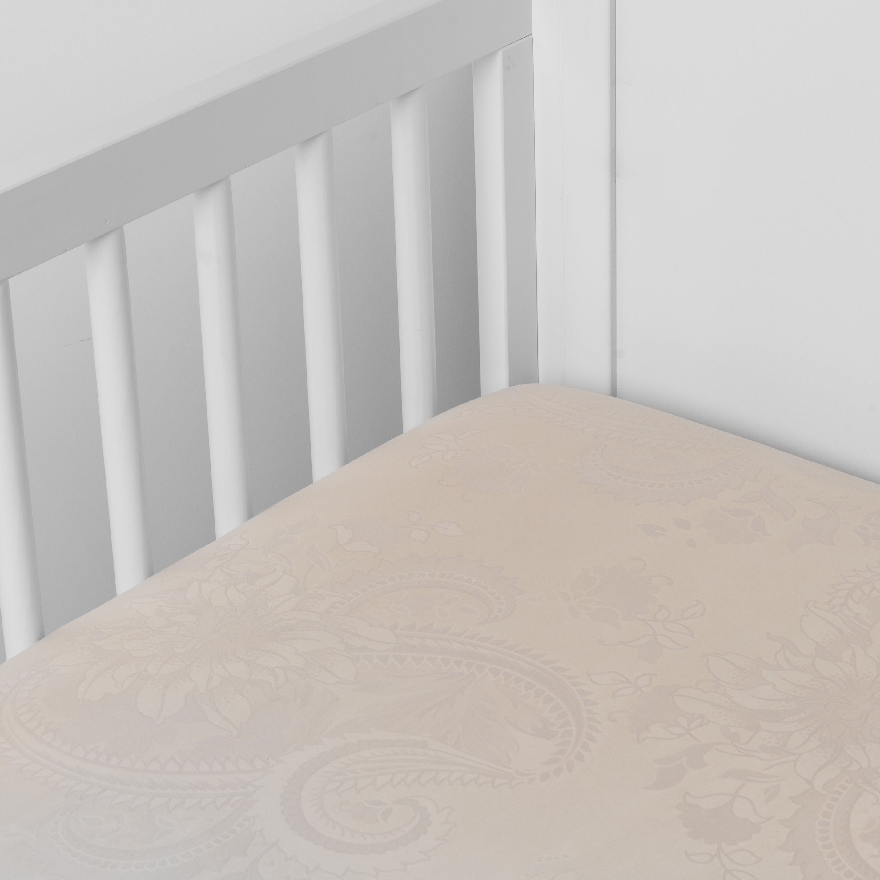 Pearl: a silk and tencel™ crib sheet shown slightly overhread and shot into the corner of a white crib.