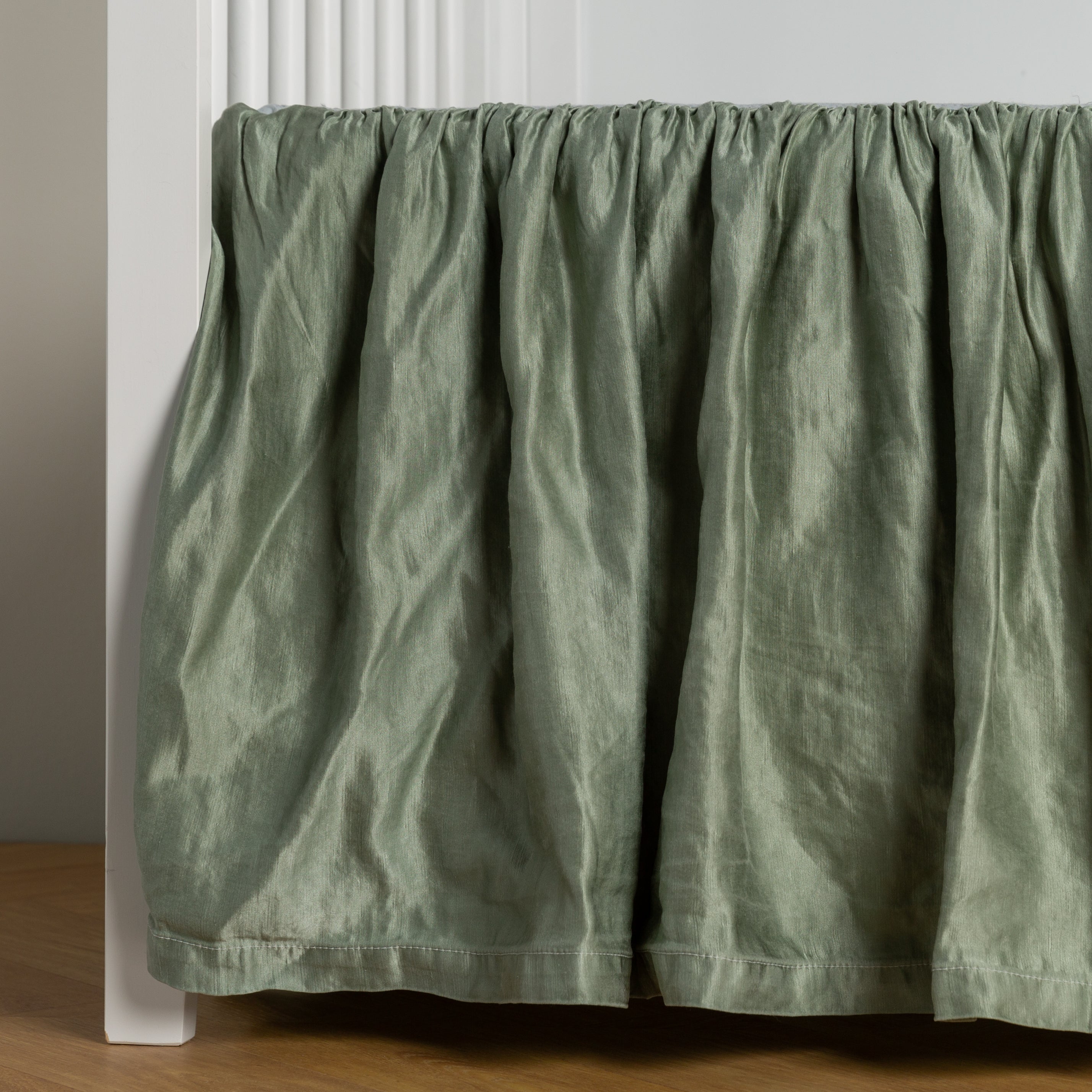 Eucalyptus: charmeuse crib skirt shown on a white crib against a white wall and medium wood floor.