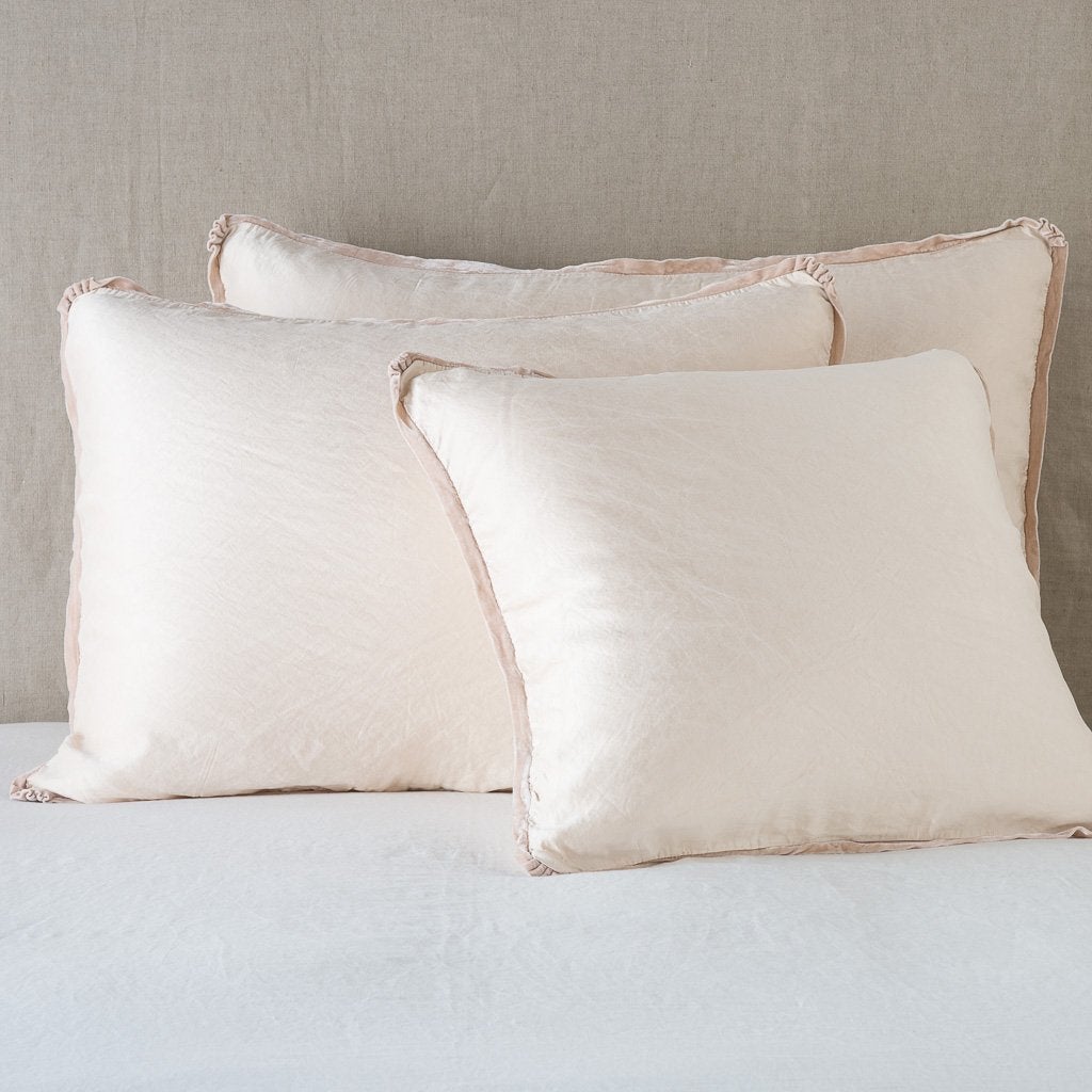 Pearl: shams leaning upright on white sheeting against a neutral headboard.
