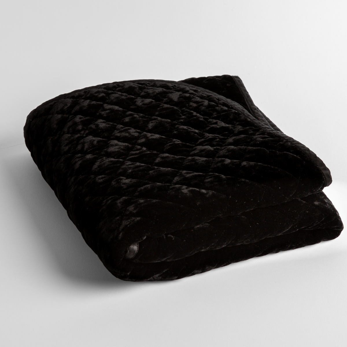 Corvino: a folded quilted silk velvet baby blanket shown from overhead to showcase quilting pattern and texture.