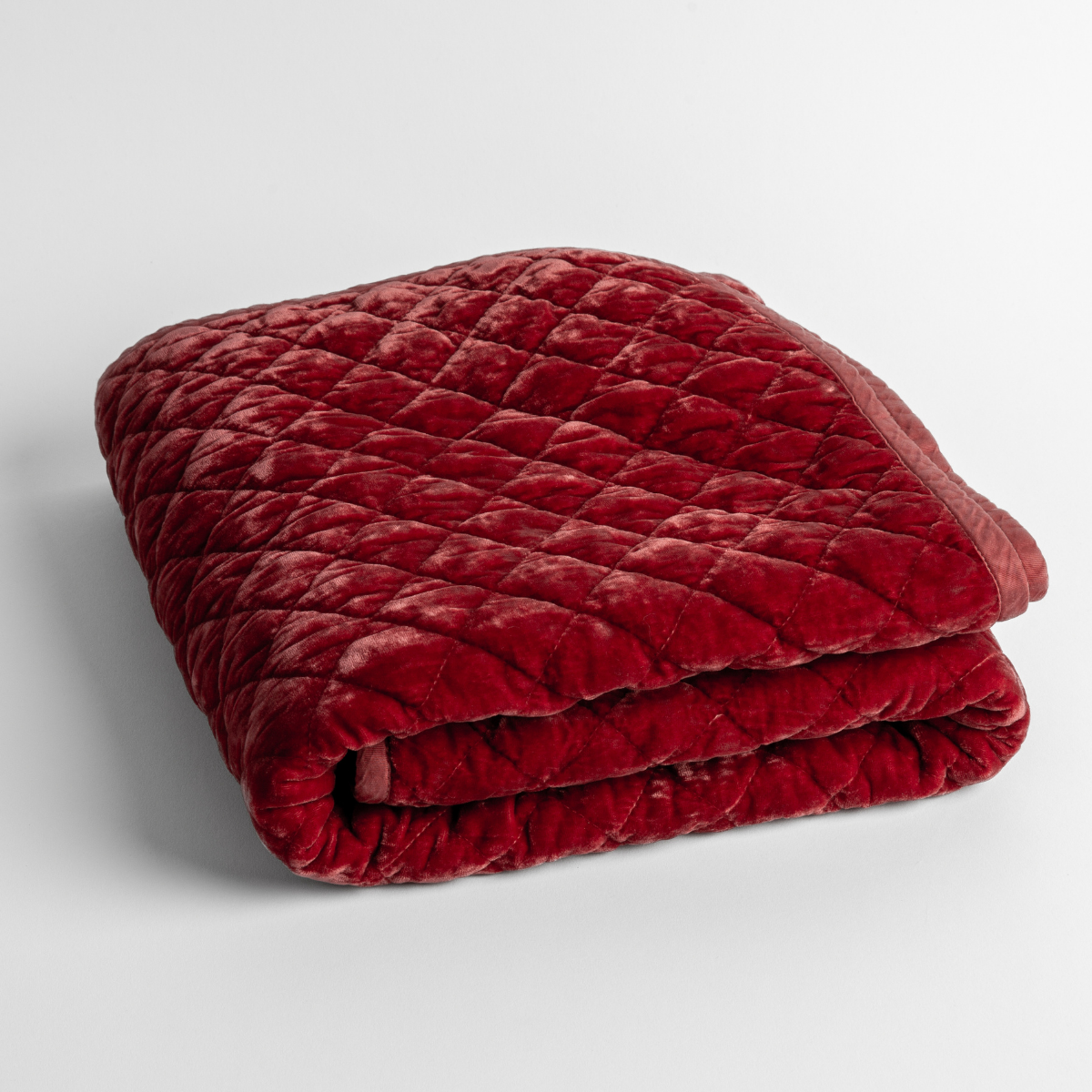 Poppy: a folded quilted silk velvet baby blanket shown from overhead to showcase quilting pattern and texture.