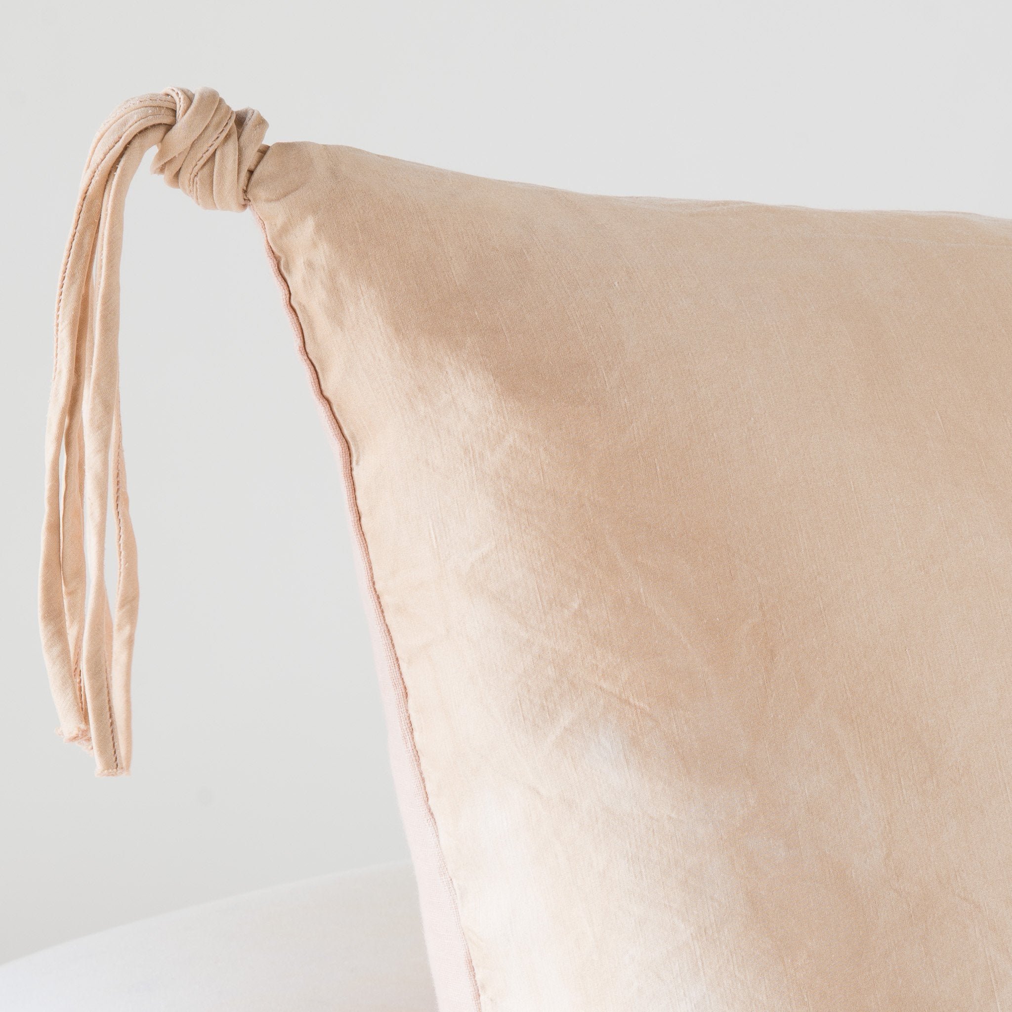 : Corner detail close-up of Taline pillow, highlighting hand-tied charmeuse tassel detail - rouge.
