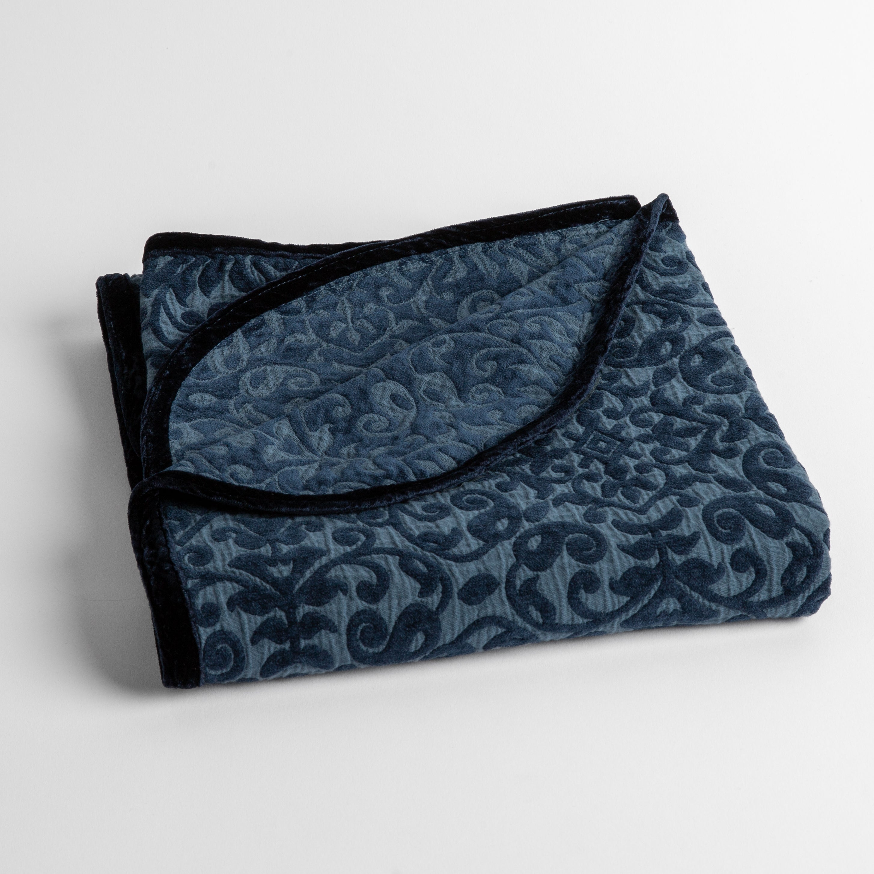 Midnight: a folded cotton chenille baby blanket trimmed in silk velvet shot overhead at a slight angle against a white background.
