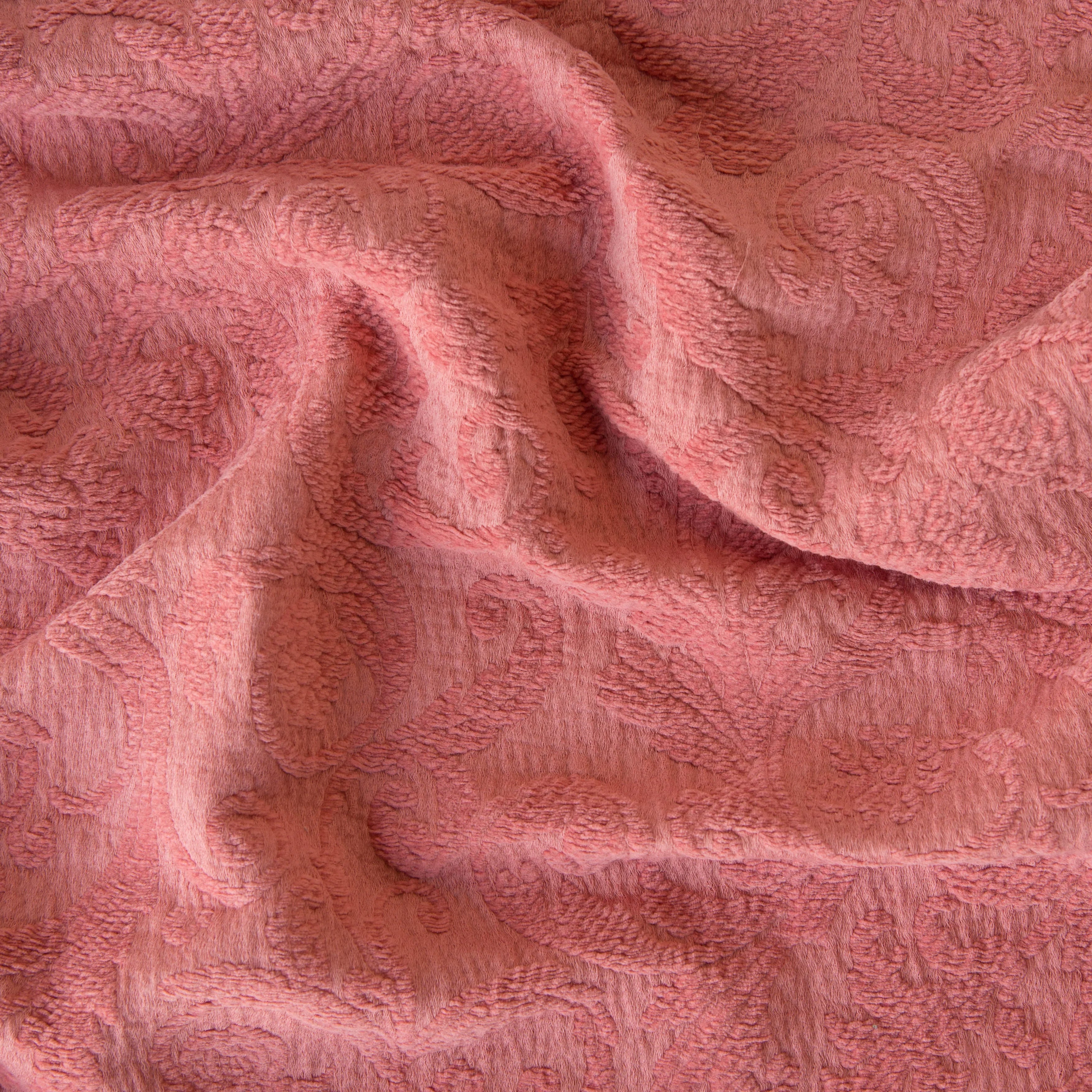 Poppy: A close up of Adele fabric in poppy, a warm coral pink. The fabric is rumpled to show the cotton damask texture.