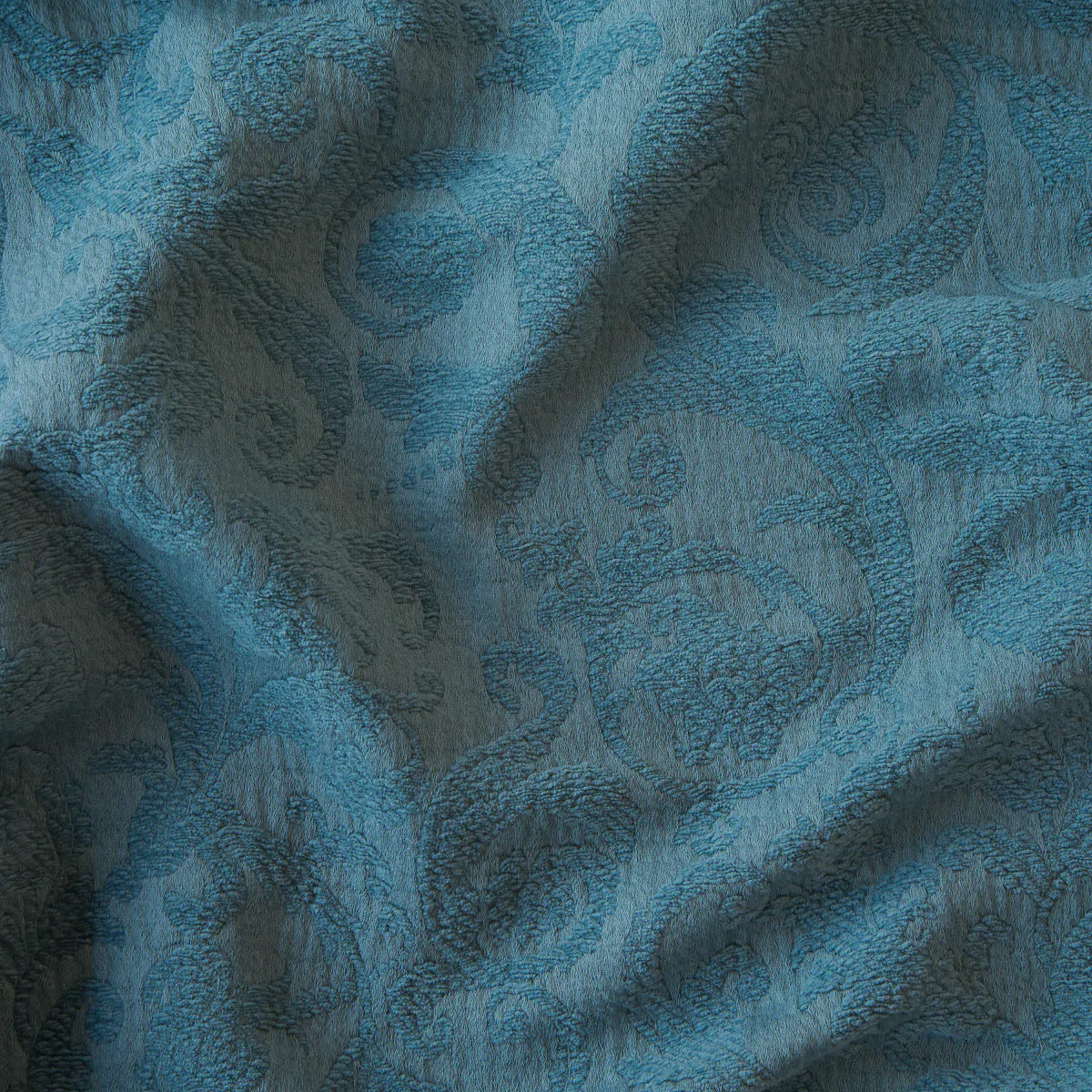 Cenote: A close up of Adele fabric in cenote, a vibrant, ocean-inspired blue-green. The fabric is rumpled to show the cotton damask texture.