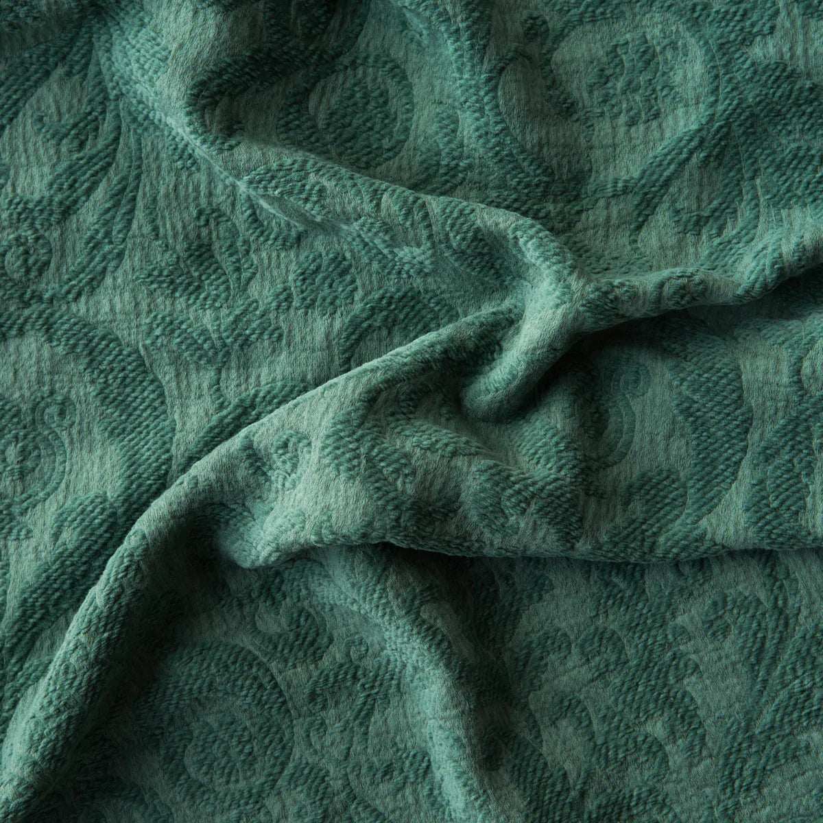 Jade: A close up of Adele fabric in jade, a rich, verdant green with subtle blue undertones. The fabric is rumpled to show the cotton damask texture.