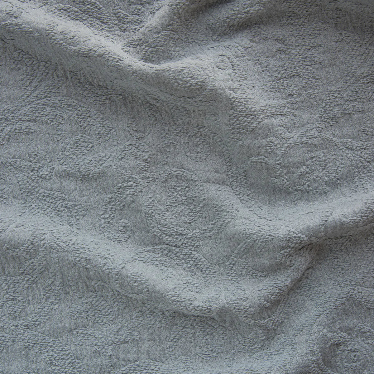Mineral: A close up of Adele fabric in mineral, a soothing seafoam blue with subtle grey-green undertones. The fabric is rumpled to show the cotton damask texture.