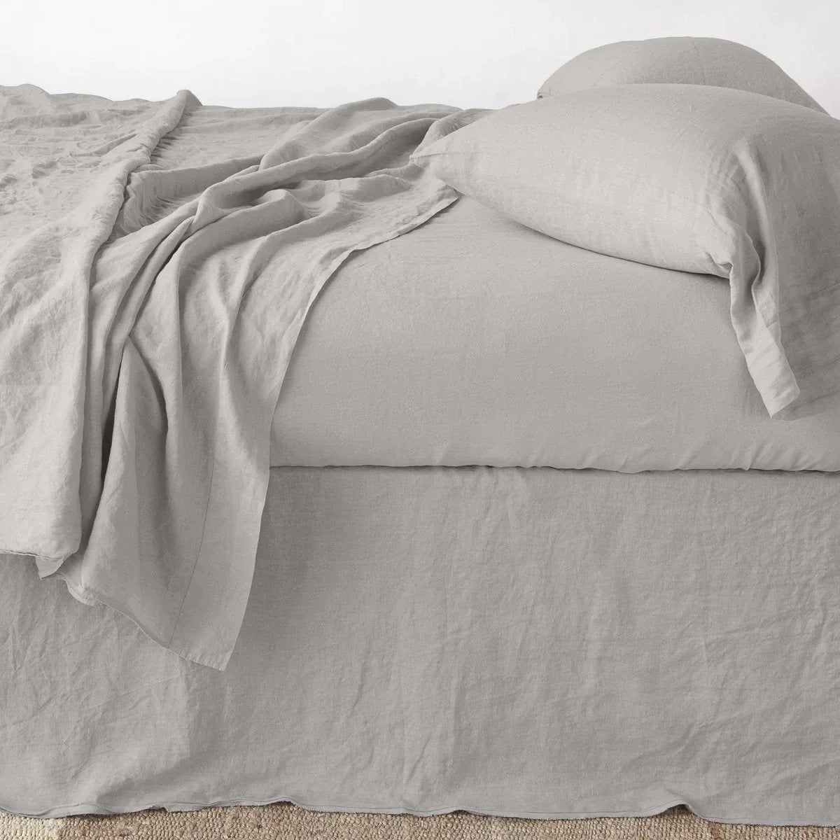 Fog: Austin bed skirt in fog shown from the side on a bed with monochromatic sheeting, highlighting its tailored, ungathered style.