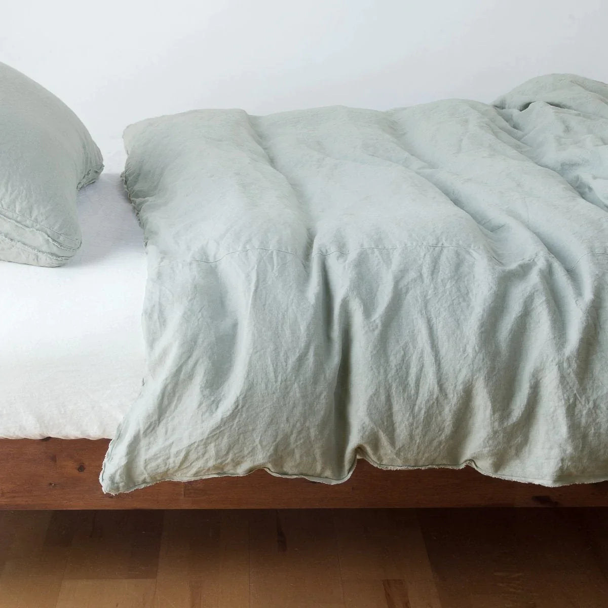 Eucalyptus: Midweight linen duvet cover in eucalyptus on a bed, side view.