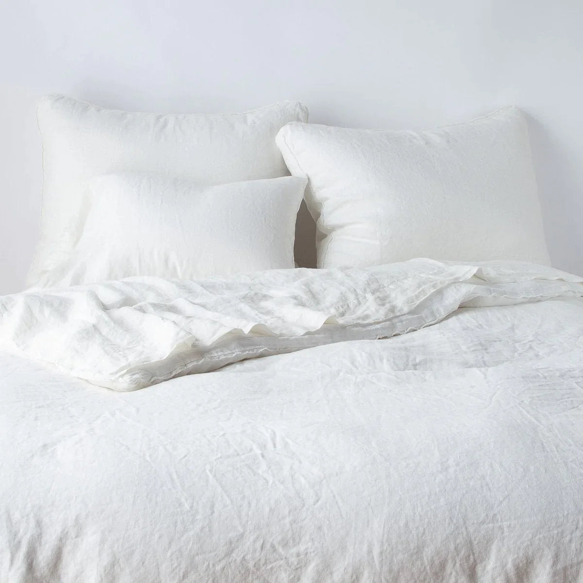 Winter White: Midweight linen shams shown from foot of bed, leaning against a plain background with monochromatic bedding.