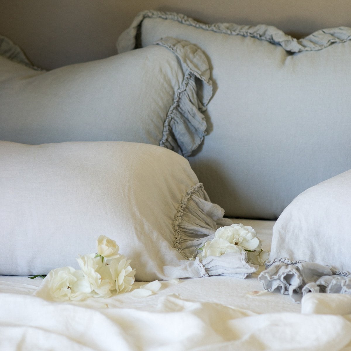 : Linen Whisper shams in mineral, layered with pillow cases and duvet cover in soft blues and greens - cropped three-quarter angle.