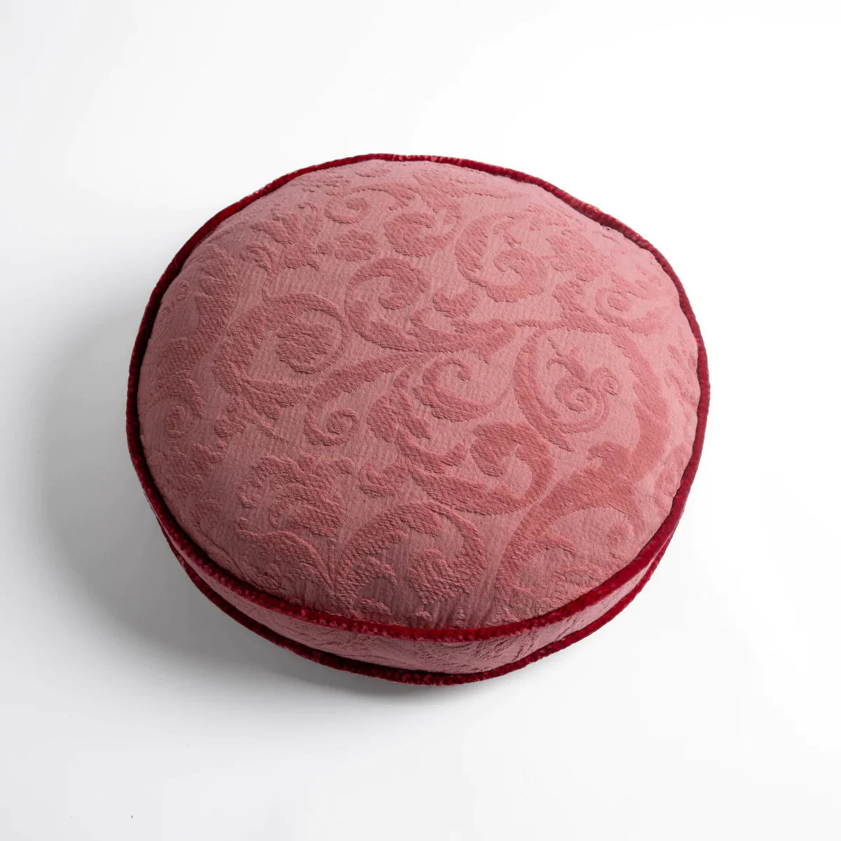 Poppy: Organic cotton damask round pillow with silk velvet trim on white background β overhead angle.